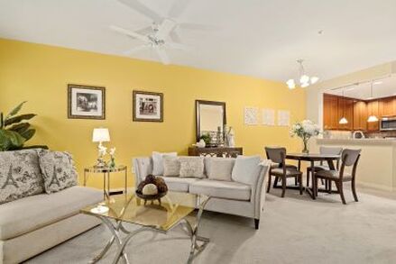 Living room and dining room with yellow accent wall and attractive staging